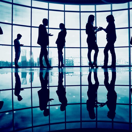 Several colleagues communicating in office against window